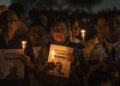 Personas sostienen velas y carteles durante una vigilia por la libertad de los presos políticos en la ciudad de Maracaibo, Venezuela. Foto: Henry Chirinos / EFE.