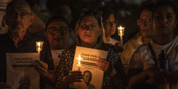 Personas sostienen velas y carteles durante una vigilia por la libertad de los presos políticos en la ciudad de Maracaibo, Venezuela. Foto: Henry Chirinos / EFE.
