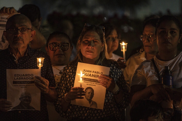 Personas sostienen velas y carteles durante una vigilia por la libertad de los presos políticos en la ciudad de Maracaibo, Venezuela. Foto: Henry Chirinos / EFE.