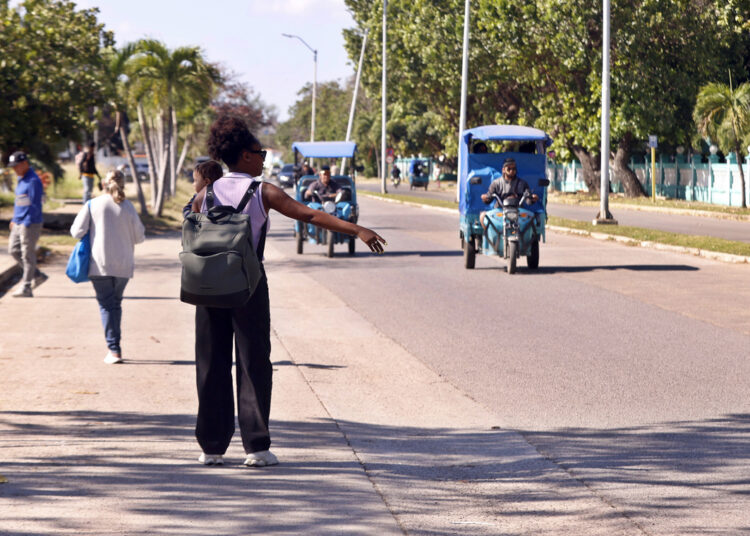 Una mujer intenta abordar un triciclo eléctrico, un medio de transporte que se ha vuelto imprescindible frente a la escasez de combustibles. Foto: EFE/ Ernesto Mastrascusa.