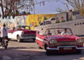Turistas pasean en autos clásicos frente a un mural del artista plástico Fuster, en Jaimanitas, La Habana. Foto: Ernesto Mastrascusa / EFE.