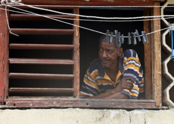 Un hombre observa desde una ventana, durante un apagón en La Habana. Foto: Ernesto Mastrascusa/EFE.