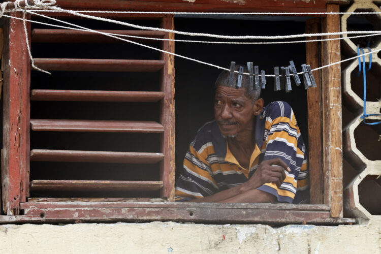 Un hombre observa desde una ventana, durante un apagón en La Habana. Foto: Ernesto Mastrascusa/EFE.