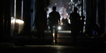 Personas caminan por una calle sin electricidad, en La Habana. Foto:  Ernesto Mastrascusa/EFE.