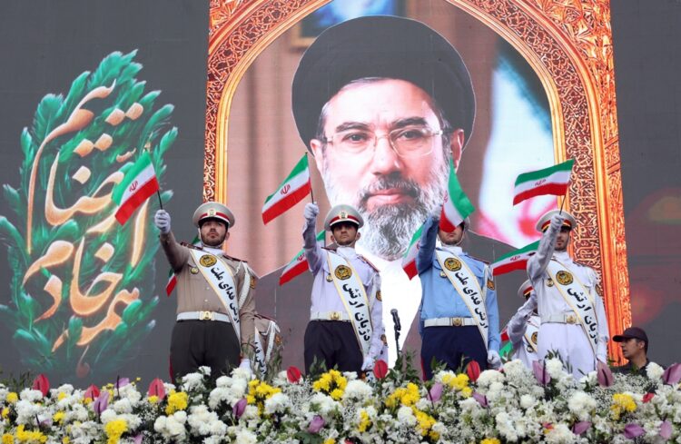 Miembros del ejército iraní ondean banderas nacionales mientras se colocan frente a un cartel del líder supremo de Irán, el ayatolá Mojtaba Jamenei, durante una manifestación en Teherán. Foto: Abedin Taherkenareh / EFE / EPA.