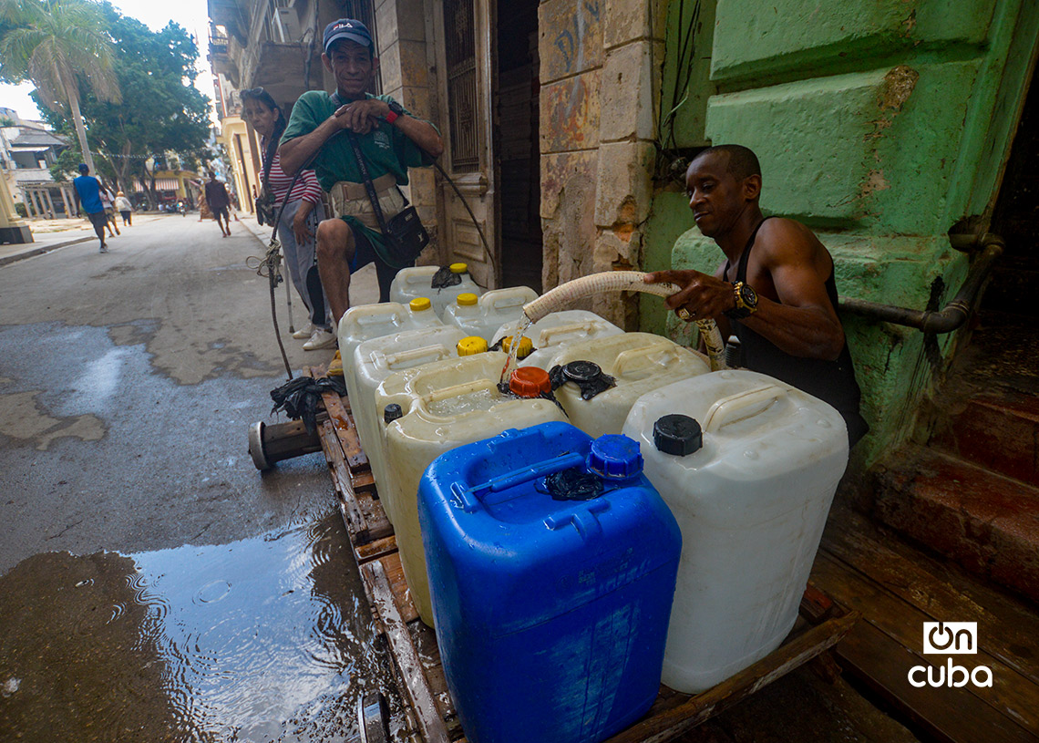 Dos hombres llenan tanquetas de agua en la calle Aguacate, en La Habana. Foto: Otmaro Rodríguez.