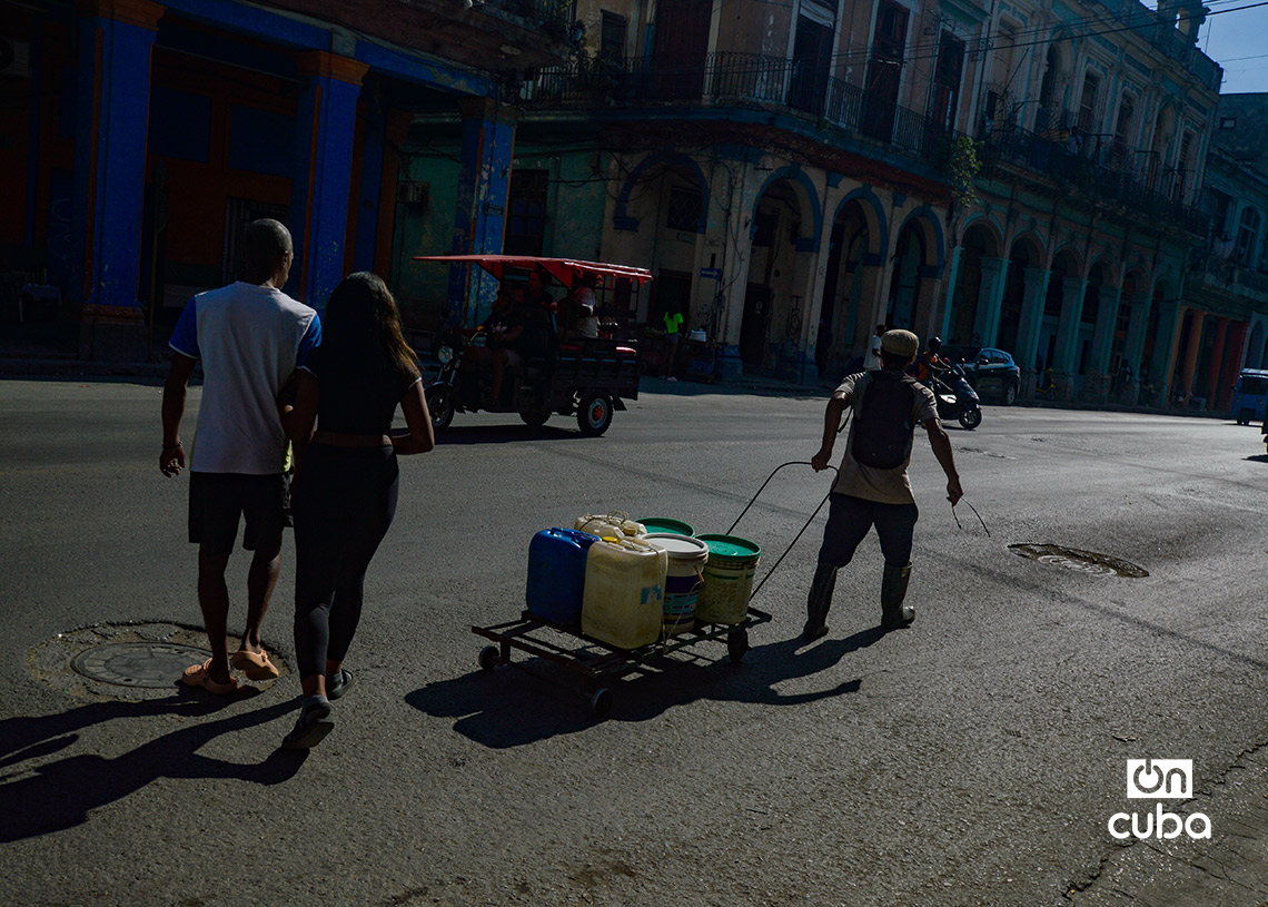 Un hombre arrastra carretilla con tanquetas de agua en la calle Reina, en La Habana. Foto: Otmaro Rodríguez.