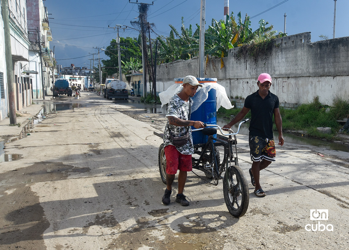 Dos hombres emplean un triciclo para transportar agua desde un punto de llenado de pipas en La Habana. Foto: Otmaro Rodríguez.