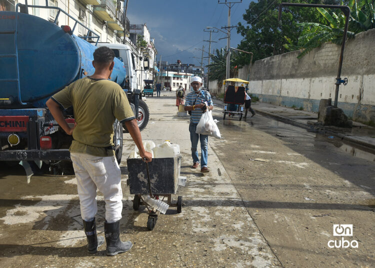 Un hombre espera para llenar pomos de agua, en un punto de llenado de pipas en La Habana. Foto: Otmaro Rodríguez.
