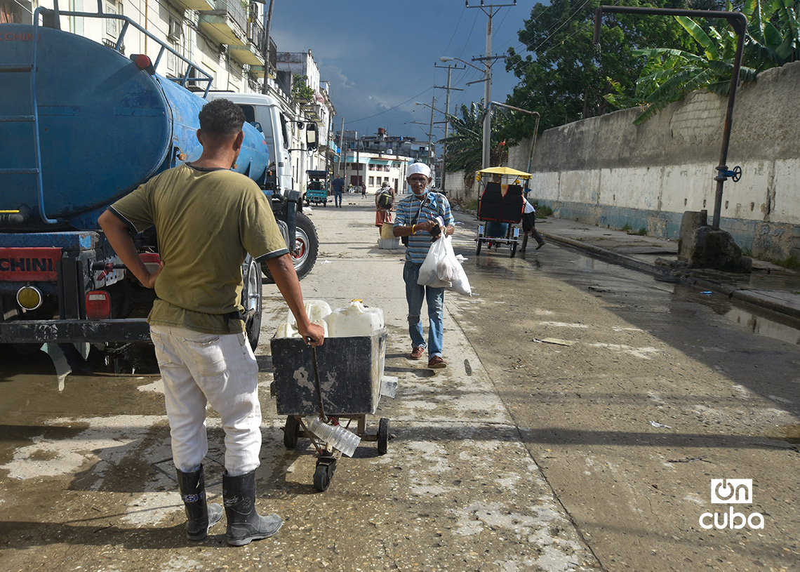 Un hombre espera para llenar pomos de agua, en un punto de llenado de pipas en La Habana. Foto: Otmaro Rodríguez.