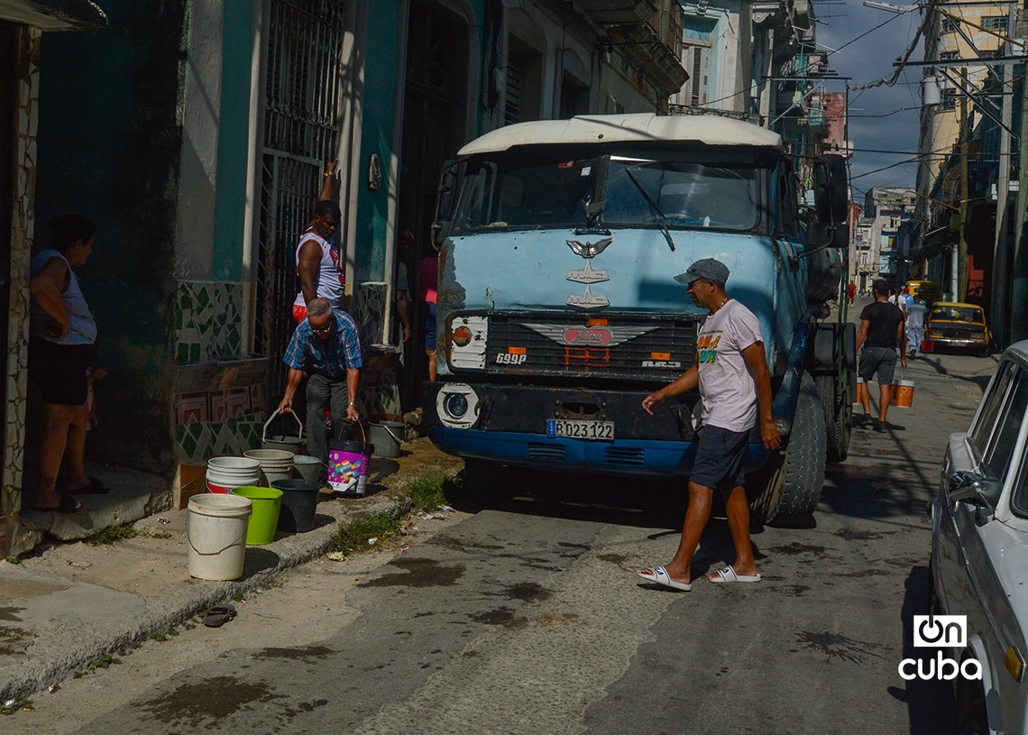 Personas cargando agua en cubos durante un apagón en La Habana. Foto: Otmaro Rodríguez.