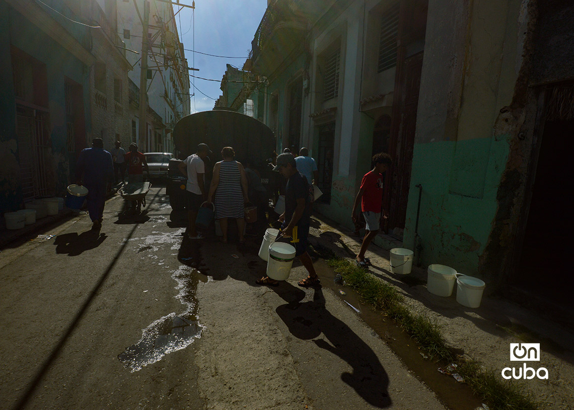 Personas cargan cubos de agua de una pipa en La Habana. Foto: Otmaro Rodríguez.