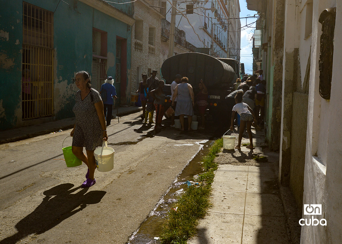 Personas cargan cubos de agua de una pipa en La Habana. Foto: Otmaro Rodríguez.