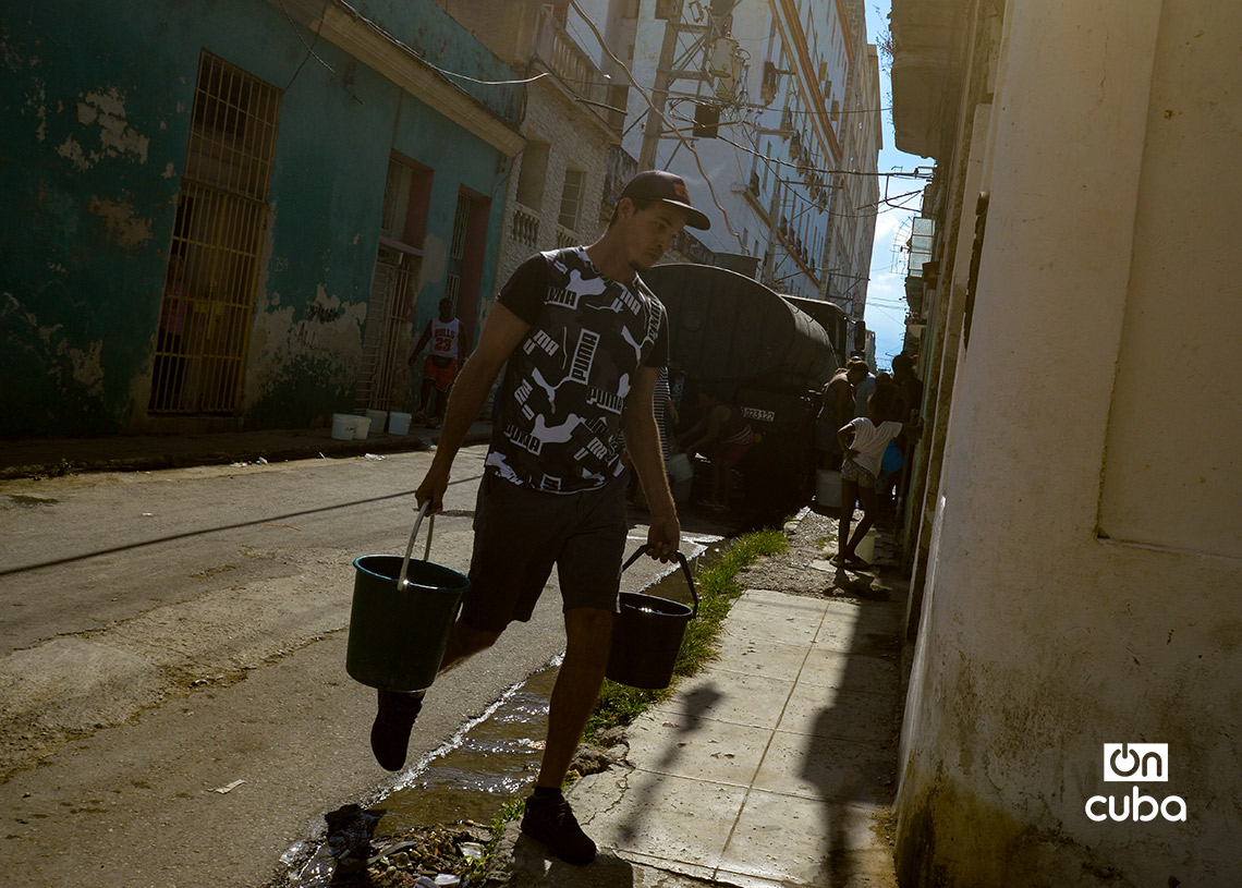 Personas cargan cubos de agua de una pipa en La Habana. Foto: Otmaro Rodríguez.