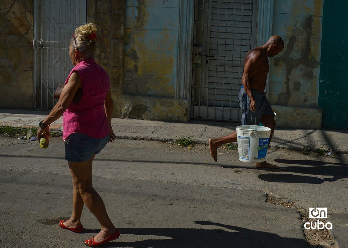 Un hombre carga cubos de agua en La Habana. Foto: Otmaro Rodríguez.