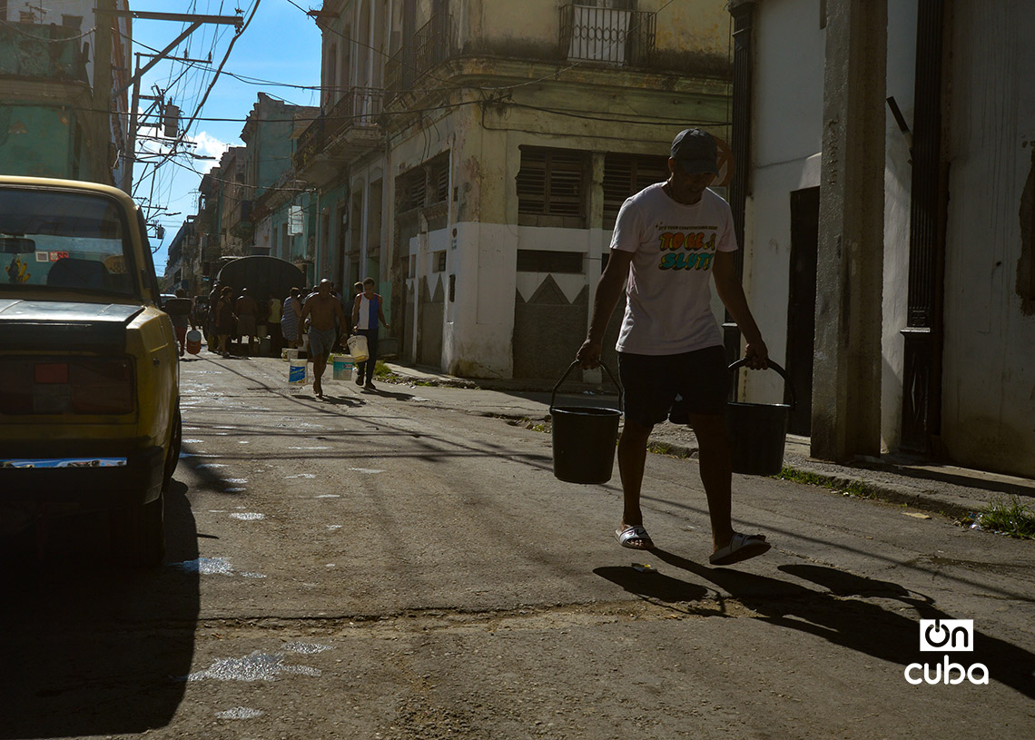 Personas cargan cubos de agua de una pipa en La Habana. Foto: Otmaro Rodríguez.
