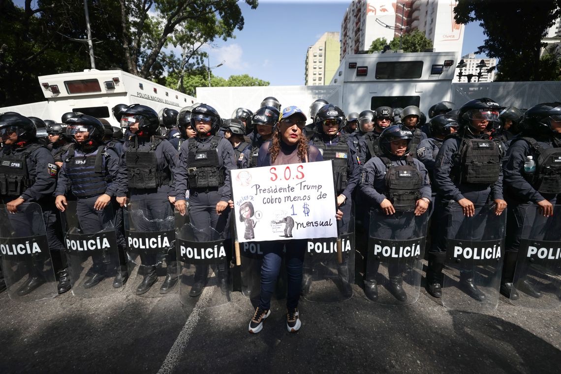 Una persona sostiene un cartel frente a un cordón policial, en una manifestación para exigir mejoras salariales en Caracas,  Venezuela. Foto: Ronald Peña R / EFE.