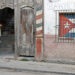 Un hombre en la entrada de un antiguo edificio, con un ventana enrejada con la bandera de Cuba, en La Habana. Foto: Ernesto Mastrascusa / EFE / Archivo.