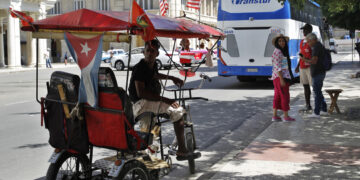Una persona espera en un bicitaxi la llegada de turistas, en La Habana. Foto:  Ernesto Mastrascusa/EFE.