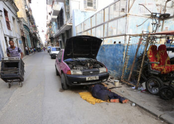 Una persona repara un automóvil en una calle este viernes en La Habana. Foto: Ernesto Mastrascusa/EFE.