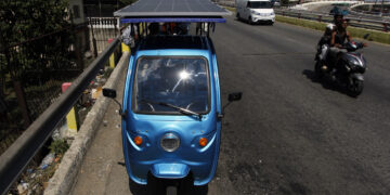 Triciclo eléctrico con un panel instalado transitando una vía habanera. Foto: EFE/STR