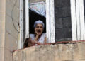 Una mujer observa desde su ventana, en La Habana. Foto:  Ernesto Mastrascusa/EFE.