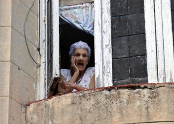 Una mujer observa desde su ventana, en La Habana. Foto: Ernesto Mastrascusa/EFE.