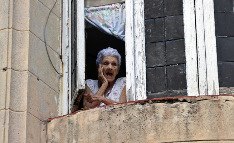 Una mujer observa desde su ventana, en La Habana. Foto:  Ernesto Mastrascusa/EFE.
