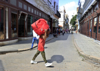 Persona cargando una maleta por una calle, en La Habana. Foto:  Ernesto Mastrascusa/EFE.