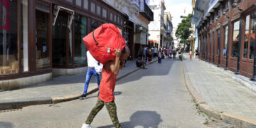Persona cargando una maleta por una calle, en La Habana. Foto:  Ernesto Mastrascusa/EFE.