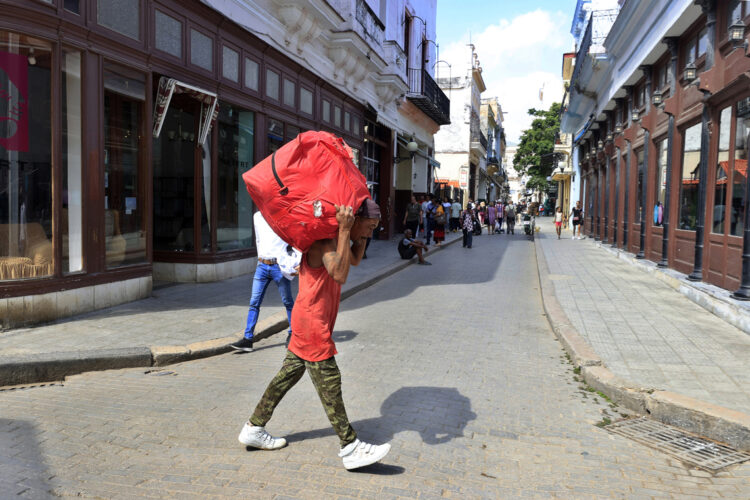 Persona cargando una maleta por una calle, en La Habana. Foto:  Ernesto Mastrascusa/EFE.