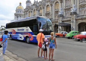 Personas observan un ómnibus de turismo en La Habana, en medio de la actual crisis energética y la drástica caída del turismo en la isla. Foto: Ernesto Mastrascusa / EFE.