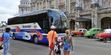 Personas observan un ómnibus de turismo en La Habana, en medio de la actual crisis energética y la drástica caída del turismo en la isla. Foto: Ernesto Mastrascusa / EFE.