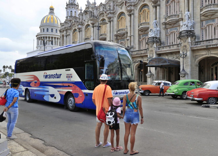 Personas observan un ómnibus de turismo en La Habana, en medio de la actual crisis energética y la drástica caída del turismo en la isla. Foto: Ernesto Mastrascusa / EFE.