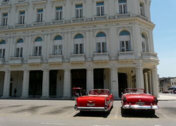 Dos solitarios descapotables en espera de algún turista frente al Gran Hotel Manzana Kempinski, en La Habana, en mayo de 2026. Foto: AMD.