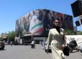 Una mujer camina junto a una enorme valla publicitaria en una calle de Teherán, Irán. Foto:  Abedin Taherkenareh/EFE.