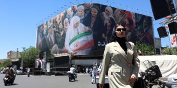Una mujer camina junto a una enorme valla publicitaria en una calle de Teherán, Irán. Foto:  Abedin Taherkenareh/EFE.