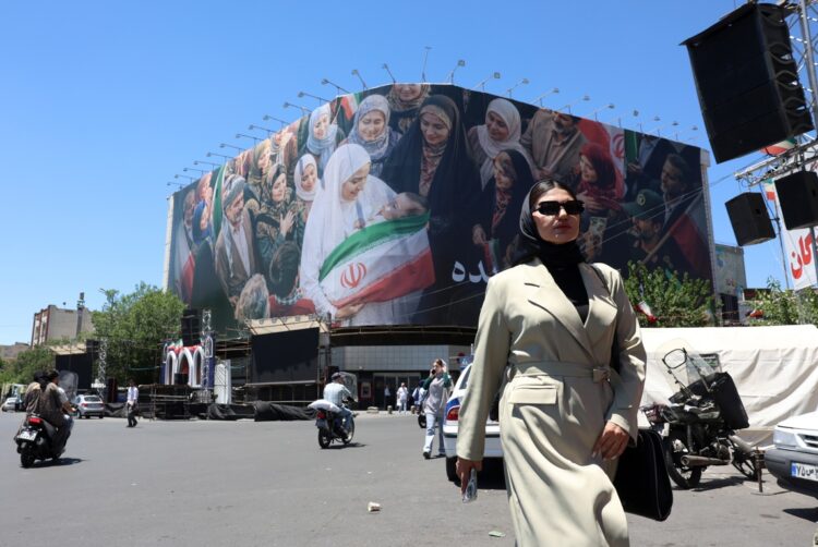 Una mujer camina junto a una enorme valla publicitaria en una calle de Teherán, Irán. Foto: Abedin Taherkenareh/EFE.
