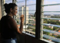 Una mujer observa la ciudad desde la ventana de su casa, en La Habana. Foto: Ernesto Mastrascusa/EFE.