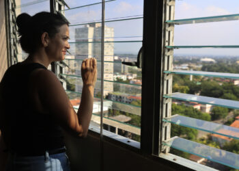 Una mujer observa la ciudad desde la ventana de su casa, en La Habana. Foto: Ernesto Mastrascusa/EFE.