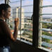 Una mujer observa la ciudad desde la ventana de su casa, en La Habana. Foto: Ernesto Mastrascusa/EFE.