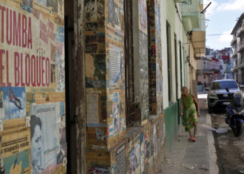 Una persona camina frente a una casa con carteles y propaganda política en su fachada, en la Habana. Foto:  Ernesto Mastrascusa/EFE.