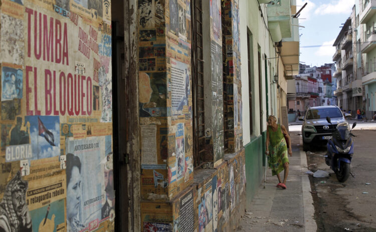 Una persona camina frente a una casa con carteles y propaganda política en su fachada, en la Habana. Foto:  Ernesto Mastrascusa/EFE.