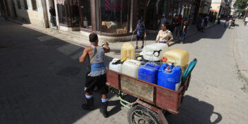 Persona llevando tanques en una bicicleta, La Habana. Foto:  Ernesto Mastrascusa/EFE.