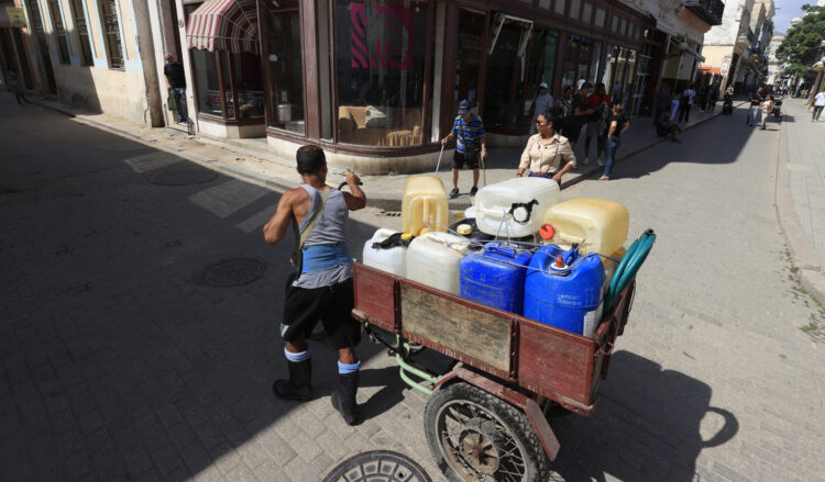 Persona llevando tanques en una bicicleta, La Habana. Foto:  Ernesto Mastrascusa/EFE.