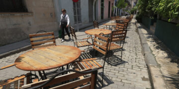 Una persona camina frente a mesas y sillas vacías en La Habana, en medio del significativo declive del turismo en Cuba en 2026. Foto: Ernesto Mastrascusa / EFE.