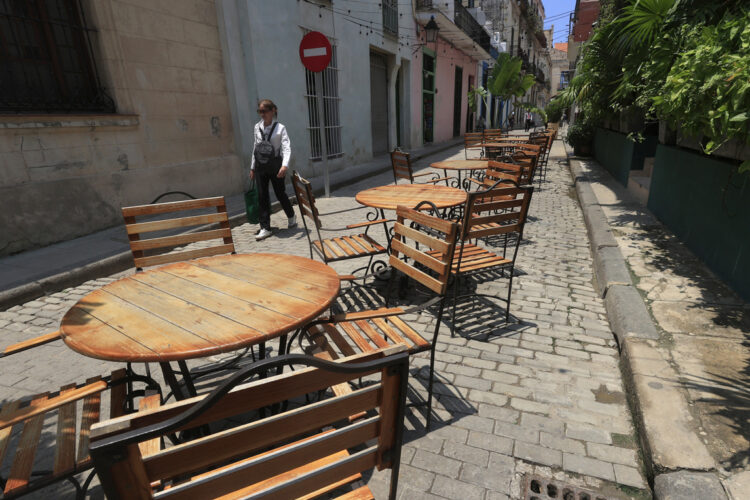 Una persona camina frente a mesas y sillas vacías en La Habana, en medio del significativo declive del turismo en Cuba en 2026. Foto: Ernesto Mastrascusa / EFE.