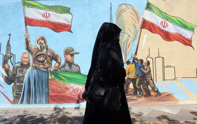 Una iraní pasa en Teherán delante de una valla que exalta el heroísmo de Irán en la guerra contra EE.UU. e Israel. Foto: Abedin Taherkenareh / EFE / EPA.