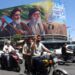 Un iraní hace el signo de la victoria mientras pasa en coche junto a una valla publicitaria de los difuntos líderes supremos iraníes, el ayatolá Ruhollah Khomeini y el ayatolá Ali Khamenei, en una calle de Teherán, Irán, el 15 de junio de 2026. Foto: EFE/EPA/ABEDIN TAHERKENAREH.