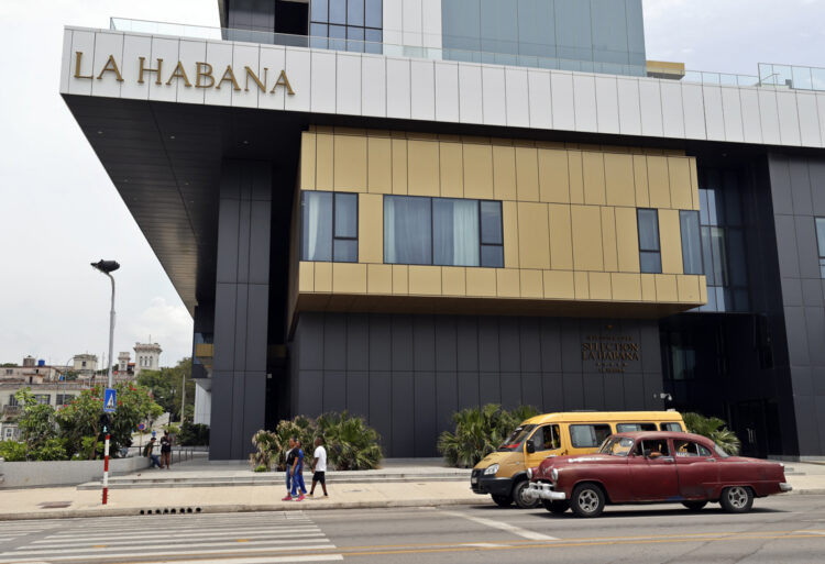 Personas transitan frente a un hotel, en La Habana. Foto: Ernesto Mastrascusa/EFE.